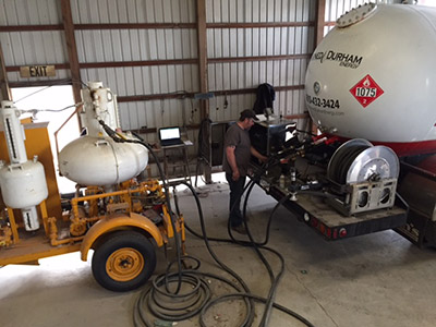 A worker makes adjustments to a propane tanker.